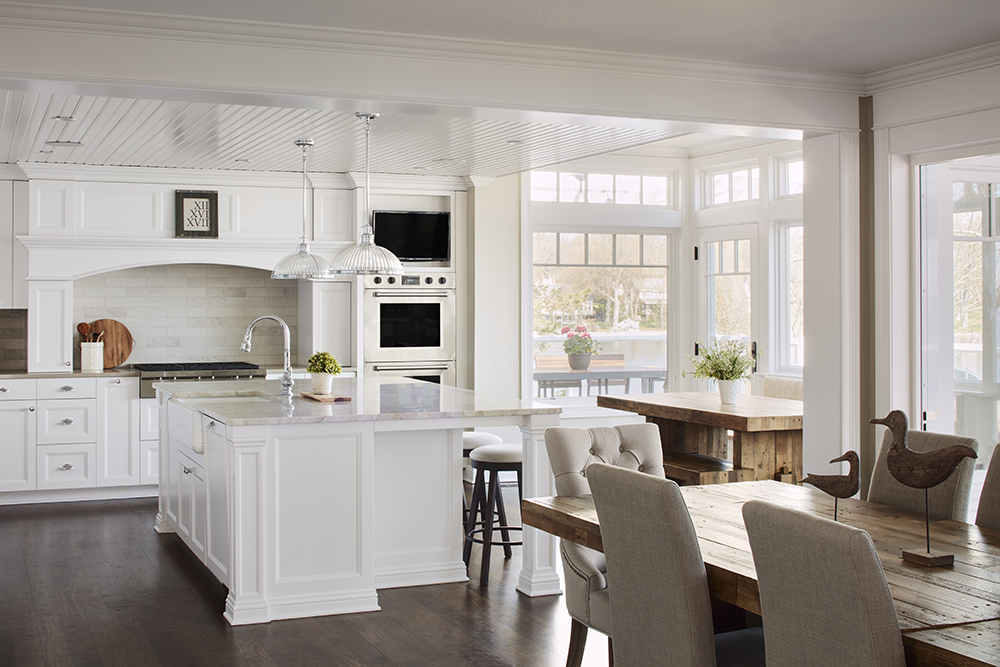 large kitchen with white cabinetry and counter tops, wood table and flooring