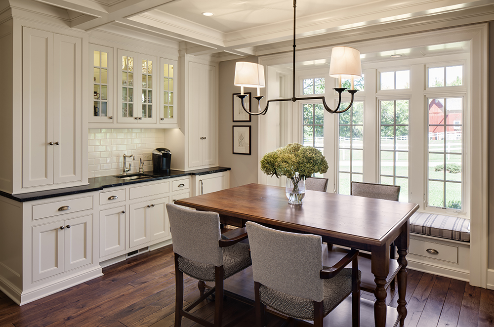 kitchen with white cabinetry and wood flooring, with large window and dining table
