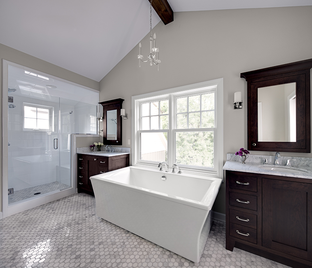 large white bathroom with tile floors, glass standing shower, and two vanities with white bathtub in between