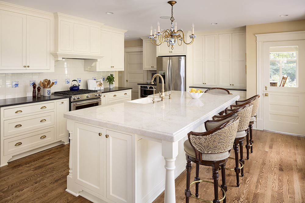 white kitchen with white cabinetry, door, and island with brown chairs and wood floor