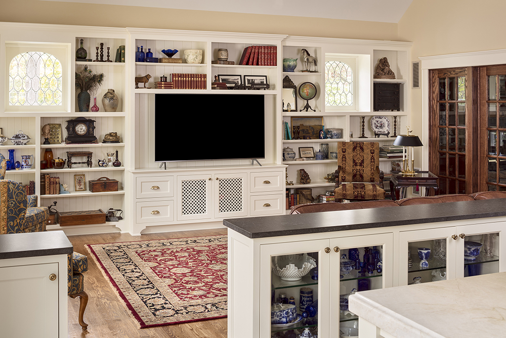 living room with white shelving, flat screen tv, and rug